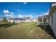 Large, grassy backyard with neighboring houses under a bright blue sky at 519 Eagle Ct, Kissimmee, FL 34759