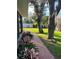 A view of the backyard featuring a brick path, lush landscaping, a mature tree, and a white privacy fence at 528 Laurel Ln, Lakeland, FL 33813