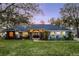 A view of this attractive single story home at dusk, showcasing its well-manicured lawn at 7026 Parliament Pl, Lakeland, FL 33809