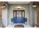 Close-up of a stylish blue front door framed by brick accents and decorative plants at 7026 Parliament Pl, Lakeland, FL 33809