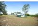 Picturesque backyard with lush trees, and a small outbuilding perfect for storage or hobbies at 705 Lake Ada Blvd, Dundee, FL 33838