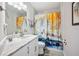 Bright bathroom featuring large mirror, stone countertop, and a shower with an abstract curtain design at 705 Lake Ada Blvd, Dundee, FL 33838