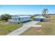 Charming blue home with solar panels and detached garage situated on expansive lawn with American flag at 705 Lake Ada Blvd, Dundee, FL 33838