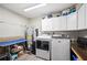 Well-lit laundry room with washer, dryer, utility sink, and ample storage space at 705 Lake Ada Blvd, Dundee, FL 33838