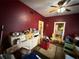 Bedroom with red walls featuring a ceiling fan, neutral trim and doorway to the kitchen at 118 S 5Th St, Haines City, FL 33844