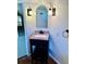 Updated half bath featuring a pedestal sink, arched mirror, and wood-look floor at 1290 S Mcadoo Ave, Bartow, FL 33830