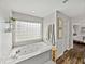 A spacious bathroom features a soaking tub beneath a glass block window and stylish decor including hardwood floors at 1301 Hidden Creek Ct, Winter Haven, FL 33880