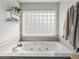 Bright bathroom with a large soaking tub and glass block window, creating a serene and spa-like atmosphere at 1301 Hidden Creek Ct, Winter Haven, FL 33880