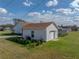 Aerial view of the home's side and back featuring a white exterior, green lawn, and a two-car garage at 1301 Hidden Creek Ct, Winter Haven, FL 33880