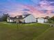 Exterior view of beautiful single Gathering home with a well-manicured lawn and detached garage at dusk at 1301 Hidden Creek Ct, Winter Haven, FL 33880