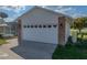 White two-car garage with brick accents and side view of an enclosed pool at 1301 Hidden Creek Ct, Winter Haven, FL 33880