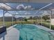 The pool is screened in and has two chairs on the pool deck with a view of the green lawn at 1301 Hidden Creek Ct, Winter Haven, FL 33880