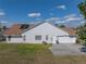 Rear exterior showcasing a white home with a brown roof, a well kept lawn, and solar panels at 1301 Hidden Creek Ct, Winter Haven, FL 33880