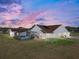 Aerial view of a white home with pool, spacious backyard, and blue/purple sky at 1301 Hidden Creek Ct, Winter Haven, FL 33880