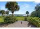 Backyard with a wooden deck overlooking the lake, surrounded by palm trees and lush greenery at 14 Lake Hollingsworth Dr, Lakeland, FL 33803