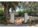 Close-up of a gated property entrance with brick paving, decorative metalwork, and lush greenery at 14 Lake Hollingsworth Dr, Lakeland, FL 33803