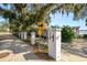 Property entrance with white pillars, decorative fence, signage, and partial view of a home with lake in the background at 14 Lake Hollingsworth Dr, Lakeland, FL 33803