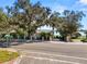 Street view of a property entrance with mature trees, a decorative fence, and a glimpse of a lake in the background at 14 Lake Hollingsworth Dr, Lakeland, FL 33803