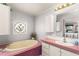 The bathroom has a large bath, floral window, and pink countertops at 140 Jackson Park Ave, Davenport, FL 33897