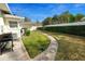 A grassy backyard with a barbecue grill, walkway, and a white fence at 1401 Easton Dr, Lakeland, FL 33803