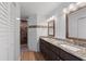 Bathroom with double granite vanity, brown cabinets, and a walk-in shower featuring decorative tile accents at 1957 Prairie Dunes N Cir, Lakeland, FL 33810