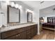 Bathroom with double vanity with granite counters, dark wood cabinets and view of Primary bedroom with king bed at 1957 Prairie Dunes N Cir, Lakeland, FL 33810