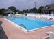 Outdoor community pool featuring lounge chairs, a fenced-in pool area, and an adjacent clubhouse at 1957 Prairie Dunes N Cir, Lakeland, FL 33810