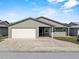 Single-story home features a two car garage, stone paver driveway, and neutral-colored exterior at 1957 Prairie Dunes N Cir, Lakeland, FL 33810