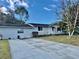 Single-story home with wide driveway, mature trees, and manicured lawn set against a blue sky at 209 Ann Ave, Dundee, FL 33838