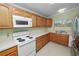 Functional kitchen with oak cabinets, white appliances, and ample counter space, designed for efficient meal preparation at 2305 State Road 33 Hwy, Clermont, FL 34714