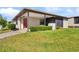 Inviting single-story home with vibrant lawn, trimmed hedges, cozy porch, and a bright red front door at 3203 Bear Creek Ln, Lakeland, FL 33810