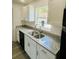 Close-up of a kitchen sink with granite countertops and white cabinets beneath a window at 3291 Alberta St, Bartow, FL 33830