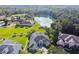 Aerial view of a single-story home overlooking a serene lake and golf course, with lush greenery and mature trees at 335 Osprey Landing Way, Lakeland, FL 33813