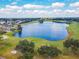 Scenic aerial view of a tranquil lake surrounded by lush golf course greenery and upscale residential homes under a partly cloudy sky at 335 Osprey Landing Way, Lakeland, FL 33813