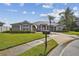 Charming one-story home with a well-manicured lawn, palm trees, and a driveway leading to a two-car garage at 335 Osprey Landing Way, Lakeland, FL 33813