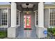 Inviting front entrance with white pillars and a vibrant red door, complemented by well-maintained landscaping at 335 Osprey Landing Way, Lakeland, FL 33813