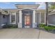 Inviting front entrance with white pillars and a vibrant red door, complemented by well-maintained landscaping at 335 Osprey Landing Way, Lakeland, FL 33813