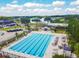 Aerial view of a pool with seating, set amidst a backdrop of lush trees, a pond and a golf course at 335 Osprey Landing Way, Lakeland, FL 33813