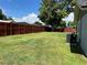 View of a large, fenced backyard featuring a well-maintained lawn and an air conditioning unit at 362 Pasco Ct, Winter Haven, FL 33884