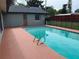 Inviting backyard pool with safety fence and red wood fence, surrounded by grass and mature trees at 362 Pasco Ct, Winter Haven, FL 33884