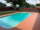 Inviting backyard pool with safety fence and red wood fence, surrounded by grass and mature trees at 362 Pasco Ct, Winter Haven, FL 33884