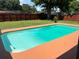 Backyard view with a vibrant turquoise pool, surrounded by a well-kept lawn and privacy fence at 362 Pasco Ct, Winter Haven, FL 33884