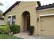 Inviting front entrance featuring a charming arched doorway, lush landscaping, and a well-manicured lawn at 4080 Prima Lago Cir, Lakeland, FL 33810