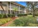 Exterior view of residential building featuring screened patios, landscaping, and mature trees at 417 Enclave Pl # 2, Lakeland, FL 33803