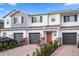 Charming townhome exterior with a gray garage door, brick driveway, and well-manicured landscaping at 5002 Rain Shadow Dr, St Cloud, FL 34772