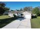 A cozy single-story home with a long driveway and a well-maintained lawn under a clear blue sky at 5121 Idlewood Ln, Lakeland, FL 33811