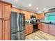 The kitchen features stainless steel appliances, warm wood cabinets and wood-look floors at 5121 Idlewood Ln, Lakeland, FL 33811