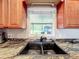 Close-up of a kitchen sink with black granite countertops and wooden cabinetry at 5121 Idlewood Ln, Lakeland, FL 33811