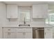 Modern kitchen featuring a stainless steel dishwasher and sink, subway tile backsplash, and white cabinets at 5908 Lunn Rd, Lakeland, FL 33811