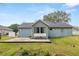 View of backyard showing the house's back exterior, a patio, and grassy area at 5942 White Tail Loop, Lakeland, FL 33811